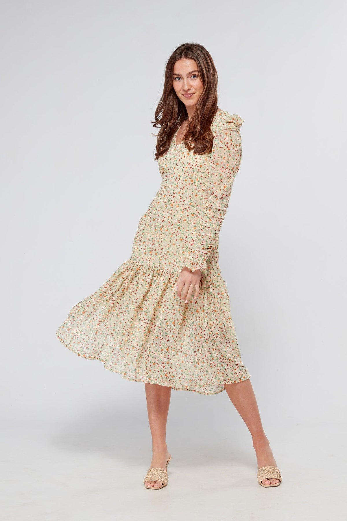 Introducing our Georgette beige floral midi dress, the perfect addition to your wardrobe for any special occasion. The dress features a stunning floral print on a beige georgette fabric that flows beautifully into a big frill. The design is nicely fitted on the waist and hips, creating a flattering silhouette, and then flowing into a frill for a feminine touch.