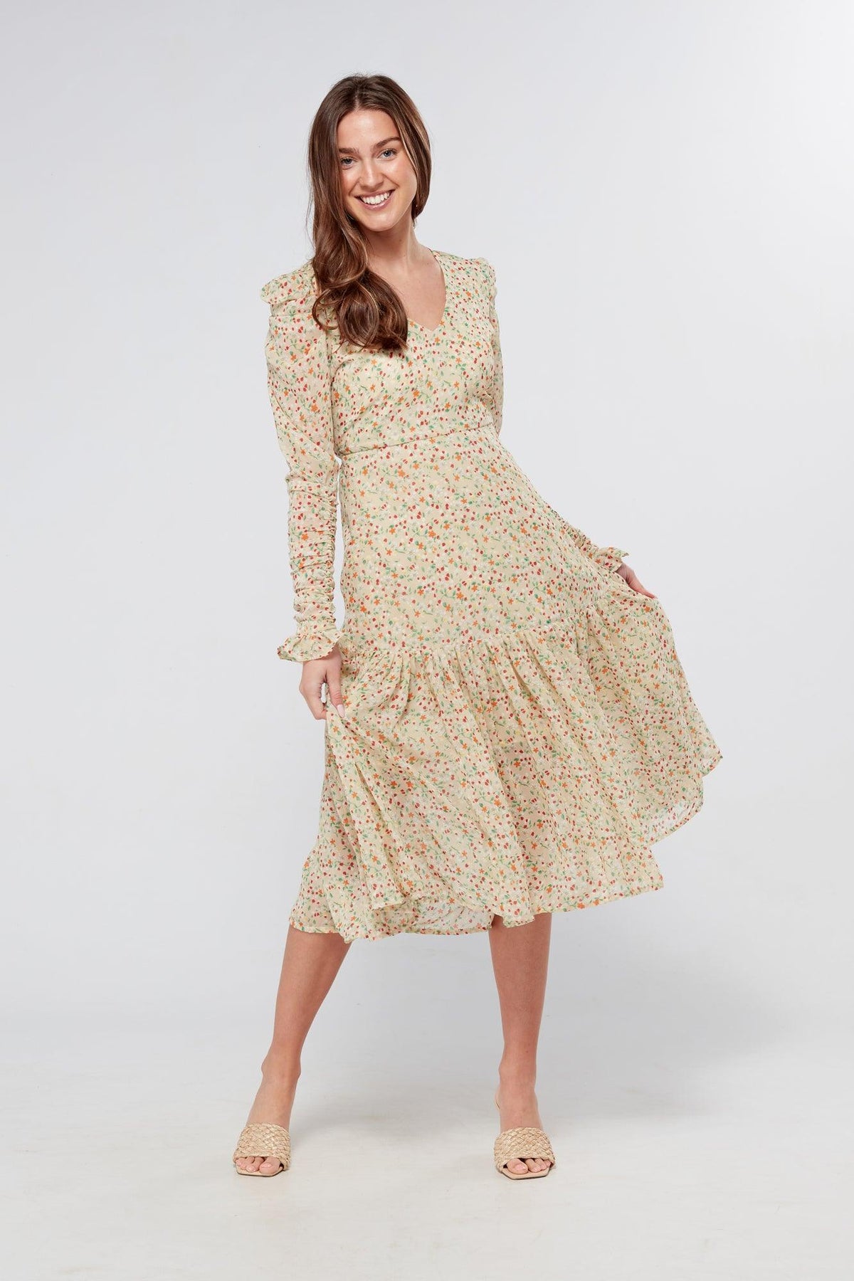 Introducing our Georgette beige floral midi dress, the perfect addition to your wardrobe for any special occasion. The dress features a stunning floral print on a beige georgette fabric that flows beautifully into a big frill. The design is nicely fitted on the waist and hips, creating a flattering silhouette, and then flowing into a frill for a feminine touch.