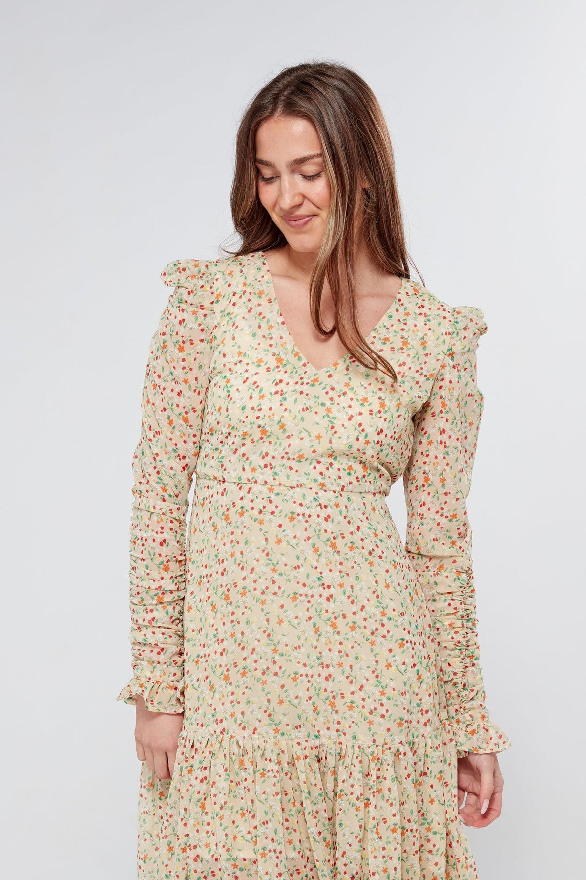 Introducing our Georgette beige floral midi dress, the perfect addition to your wardrobe for any special occasion. The dress features a stunning floral print on a beige georgette fabric that flows beautifully into a big frill. The design is nicely fitted on the waist and hips, creating a flattering silhouette, and then flowing into a frill for a feminine touch.